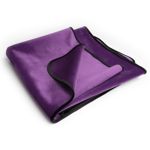 The Liberator Fascinator Travel Sized Waterproof Sex Blanket, folded in purple velvet with black trim, is neatly displayed on a white background.
