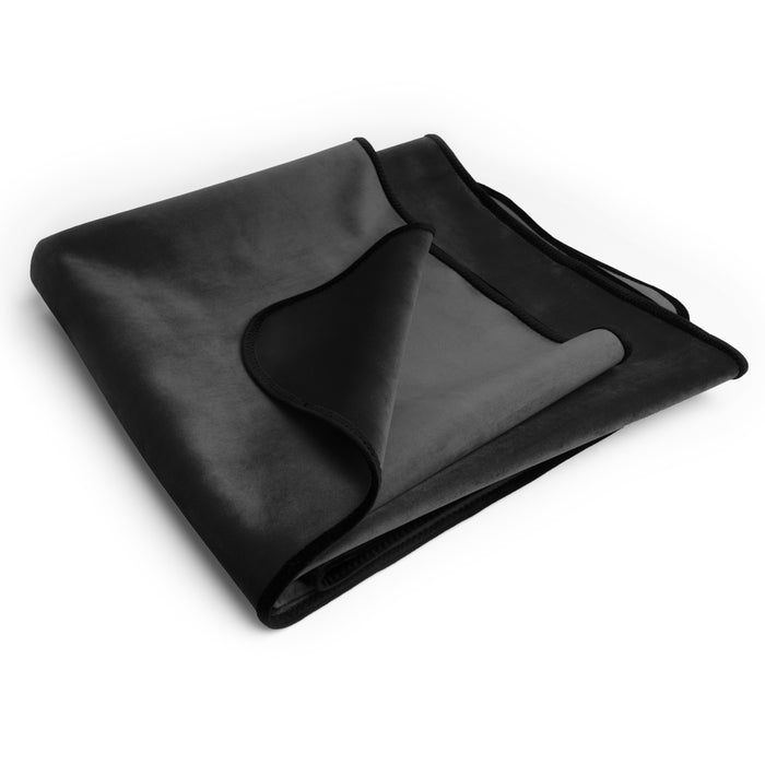 The Liberator Fascinator Travel Sized Waterproof Sex Blanket, featuring two-tone black and dark gray moisture barrier fabric, is neatly folded on a white background with a corner turned over to show the contrasting soft surfaces.