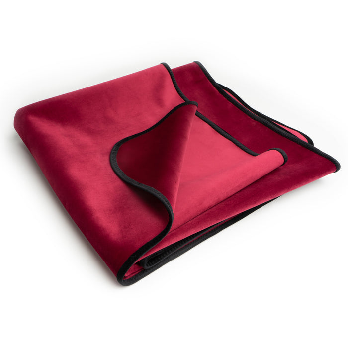 The Liberator Fascinator Travel Sized Waterproof Sex Blanket, shown folded in red velvet with black trim on a white background, offers a stylish and protective moisture barrier.