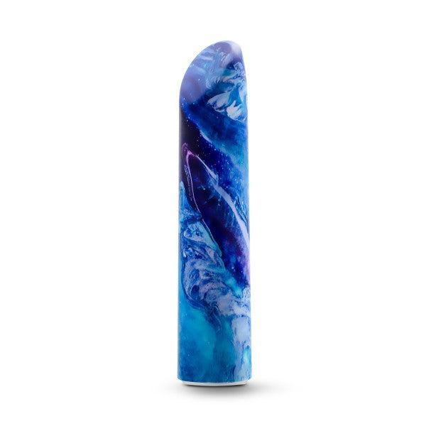 The Limited Addiction Power Bullet Vibe - Mesmerize by Blush features a sleek, abstract design with a vibrant blue and purple color scheme. The pattern on the vibe resembles fluid, swirling waves, giving it an artistic and dynamic appearance. USB rechargeable for convenience, the vibe stands upright against a plain white background.