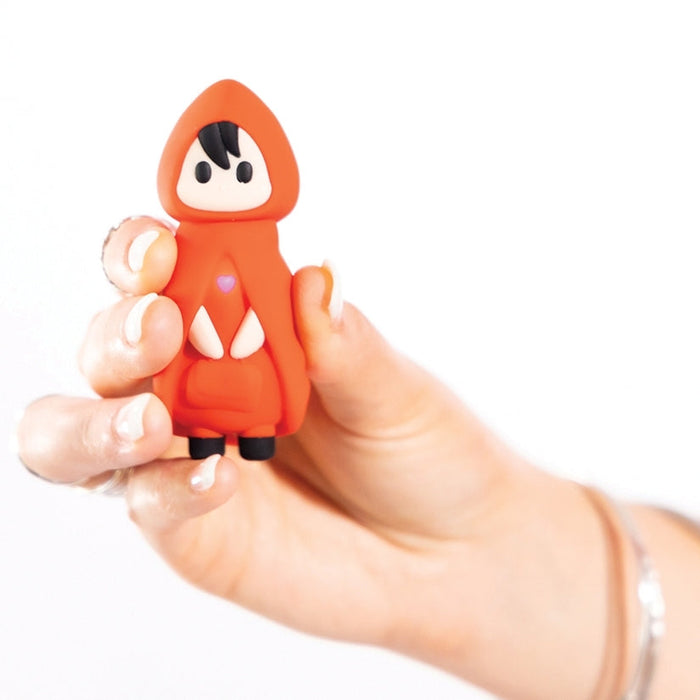 A hand holds the Little Red Discreet Powerful Bullet Vibrator, shaped like a small red-hooded figure with black hair and shoes, plus a heart on its chest—its playful design stands out charmingly against the plain white background.