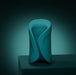 A sleek teal Lovense Gush 2 oscillating masturbator with smooth curves and a circular pattern stands on a dark surface against a gradient teal background, offering modern design and app compatibility for a hands-free experience.