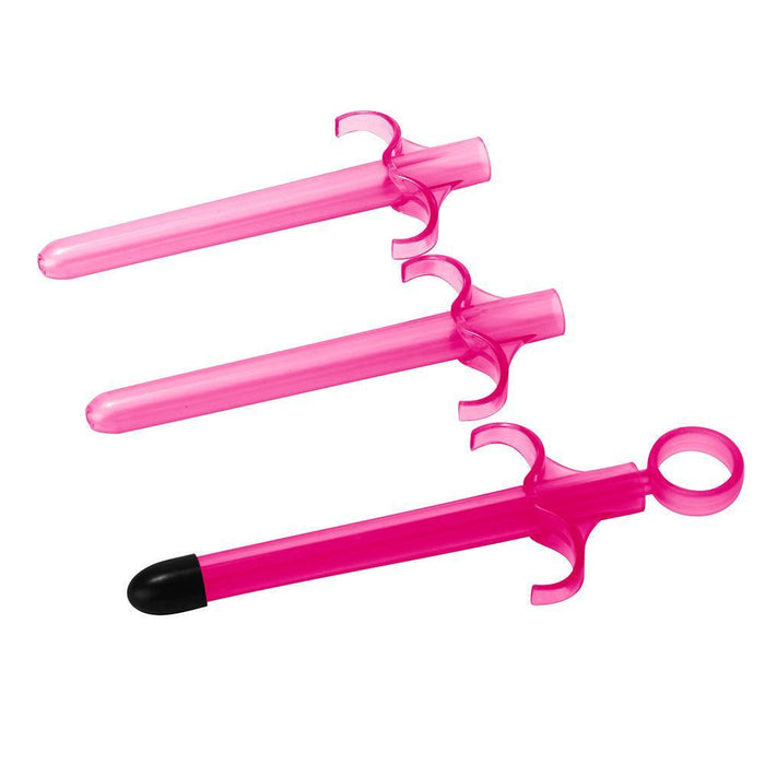 The XR Brands Lubricant Launcher 3-Pack Pink includes three pink plastic syringes with finger grips and a loop at the plunger end; the top two syringes feature smooth tips, while the bottom syringe comes with a black soft rubber tip for feeding or use as a lubricant launcher.