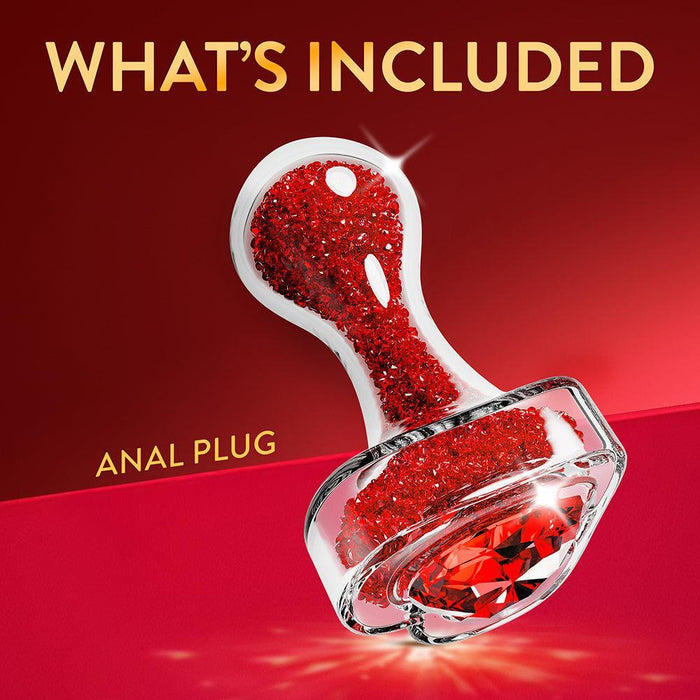 The Lustre Glass Butt Plug with Gem Base & Red Crystals is shown on a red background, featuring "WHAT'S INCLUDED" above and "ANAL PLUG" beside the product.