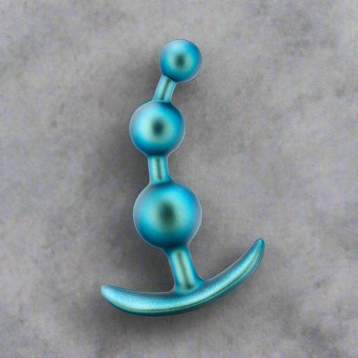 The Matrix First Time Soft Silicone Anal Beads in Shimmery Blue by Blush feature a series of three graduated spherical beads, increasing in size from top to bottom. This blue metallic anal toy includes silicone beads and a curved handle at the base, ensuring easy removal and a comfortable fit with StayPut technology.