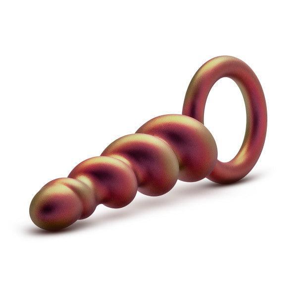 The Matrix First Time Soft Silicone Spiral Anal Beads with Finger Loop by Blush is a smooth-textured, metallic anal toy that features multiple bulbs and a gradient color of bronze and purple hues. Resembling a unicorn horn, its width gradually increases toward the ring end, making it perfect for orgasmic anal play.