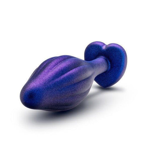 The Matrix Wavy Bling Plug with Sparkly Heart Base by Blush is a metallic, purple, heart-shaped butt plug featuring a bulbous, fluted design and a rounded base. Posed against a white background, this beginner-friendly plug combines style and comfort for those new to the experience.
