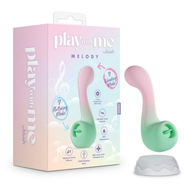 The Melody Double Ended Licking Tongue & G-Spot Vibrator, in pastel colors and wavy design, stands on a white charging base next to packaging that reads "play with me MELODY" and showcases 7 fluttering modes plus body-safe silicone.