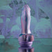 The Mythical Long Thick Vibrating Fantasy Dildo in Pastel Ombre, shaped realistically in lavender and pearl silicone, stands upright on a reflective surface against a dreamy abstract purple background.