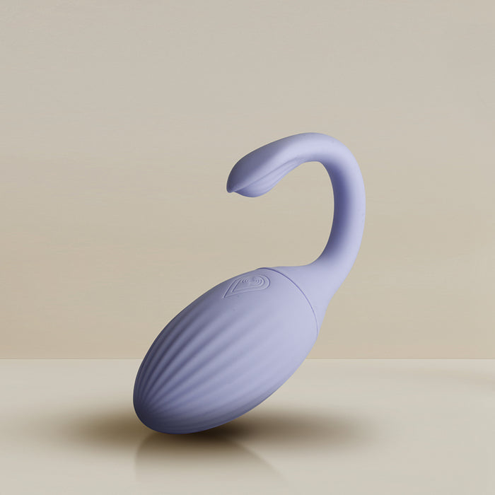 The Niya Rechargeable Kegel Exerciser and Vibrator with Remote is a light purple, oval-shaped massager featuring a ribbed texture and a curved handle, shown against a neutral beige background.