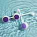 Two white and purple kegel balls from the Wellness Kegel Ball Training Kit for Pelvic Floor Health float on blue water, creating gentle ripples—an elegant reminder of strengthening your pelvic floor with this quality kit.