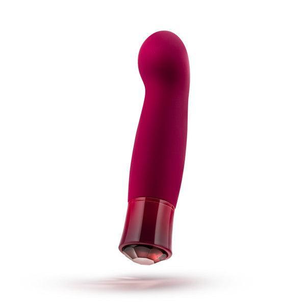 The Oh My Gem Classy Garnet Warming Internal & External Vibrator by Blush, available in a striking red and pink color, features a curved, smooth design with a translucent base. It offers versatile vibrating functions designed to ignite sexual passion and is elegantly displayed against a white background.