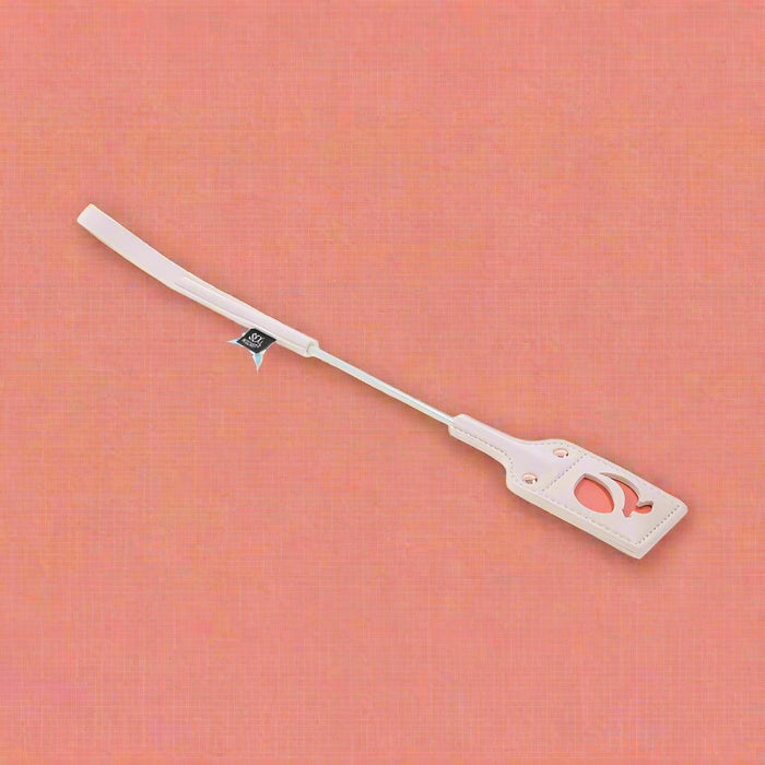 Displayed is a beige luggage tag with a long strap, incorporating a transparent window that reveals a red illustration for a playful accent. A small black tag is affixed to the strap. This minimalist and functional design captures the simplicity reminiscent of the Peaches 'n Cream Impressions Crop by Sportsheets.