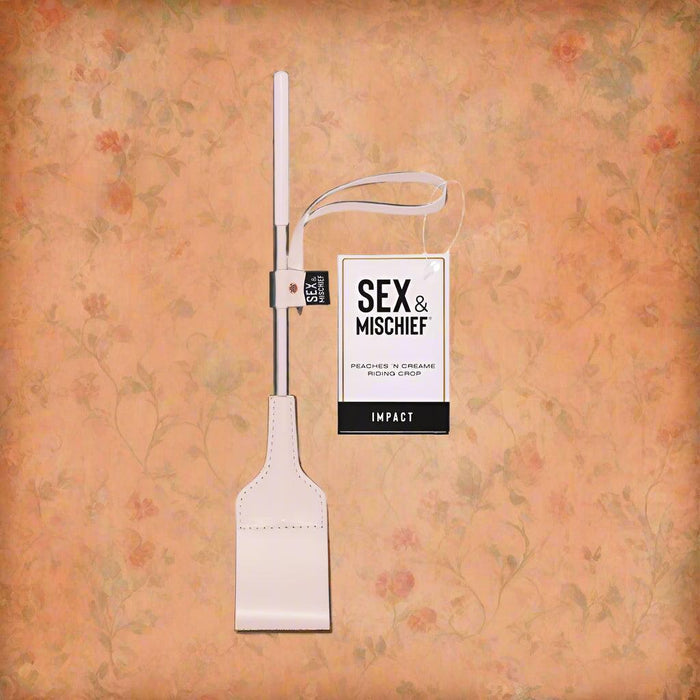 A pink faux leather riding crop with a rectangular flat end, labeled "Peaches 'n Cream Riding Crop" by Sportsheets, perfect for adding a touch of playful sophistication to intimate moments.