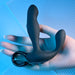 A hand holding the Playboy Come Hither Motion Vibrating Prostate Massager by Evolved Novelties against a blue-lit background. The black, curved massager, with its looped handle, boasts a smooth, ergonomic design and appears to be made of silicone. Featuring 10 vibration speeds and a come hither motion, the lighting enhances its sleek and modern appearance.