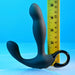 The Playboy Come Hither Motion Vibrating Prostate Massager by Evolved Novelties, a black curved device with two bulbous ends and a looped handle, stands upright next to a vertical yellow ruler, measuring approximately 5.5 inches. Featuring 10 vibration speeds and USB rechargeable capabilities, the background is a smooth surface with a gradient blue color.