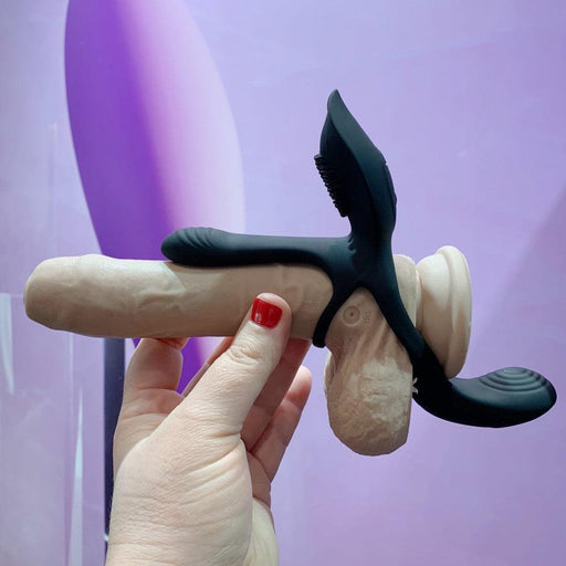 Hand holding an Evolved Novelties Playboy The Three Way Couples Vibrating Cock Ring & Enhancer with ergonomic wings, designed for perineum stimulation.