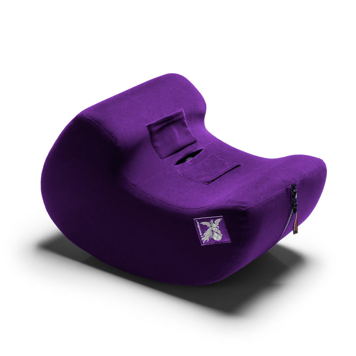 The Liberator Pulse – Ergonomic Straddling Toy Mount is a purple, contoured cushion with a zippered side pocket and a white graphic label, designed for hands-free fun. It's shown against a white background.