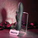 The Rabbit Hole Double Ended G-Spot and Clitoral Suction Rabbit Vibrator by Evolved Novelties, a black dual-motor device with a sleek, ergonomic design, is displayed on a clear stand. The vibrator offers clitoral and G-spot stimulation with two prongs and a textured, curved tip. Crafted from premium silicone, it is positioned on a counter with black stones in the background. The stand is labeled "Evolved.