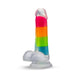 The Rainbow Rave Glow in the Dark 6.5 Inch Silicone Dildo by Blush features a vibrant array of rainbow stripes in pink, orange, yellow, green, and blue with a realistic feel and a secure suction base that allows it to stand upright.