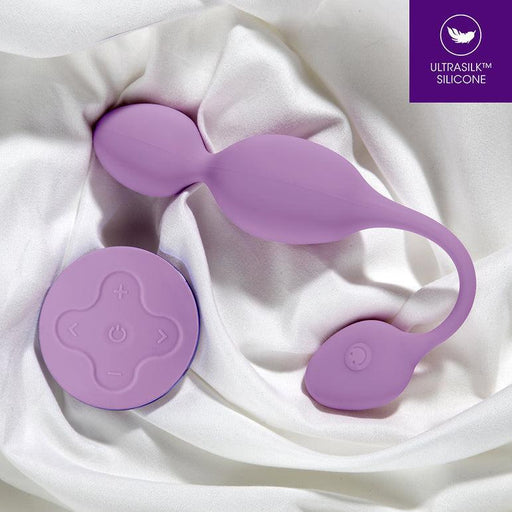 The Raine Vibrating Kegel Ball with Remote Control, crafted from purple silicone, rests elegantly on white satin fabric. It includes kegel balls for pelvic floor strengthening and a wireless remote with power and intensity buttons. A corner logo states "UltraSilk Silicone.