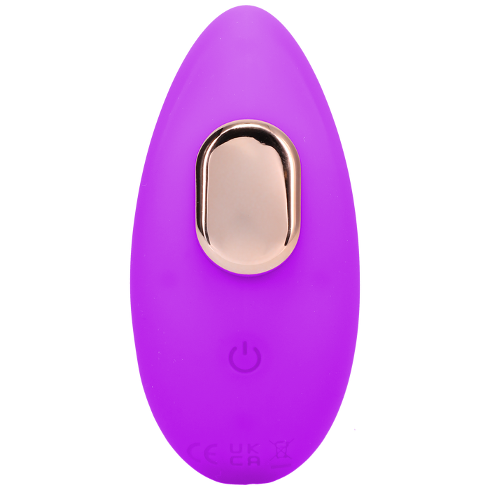 A small, oval-shaped, purple Remote Controlled Panty Vibrator for Beginners in a Bag by Doc Johnson, featuring a gold button on top and a power symbol near the bottom. The device appears to be made of a smooth, soft material and has an eco-friendly design.