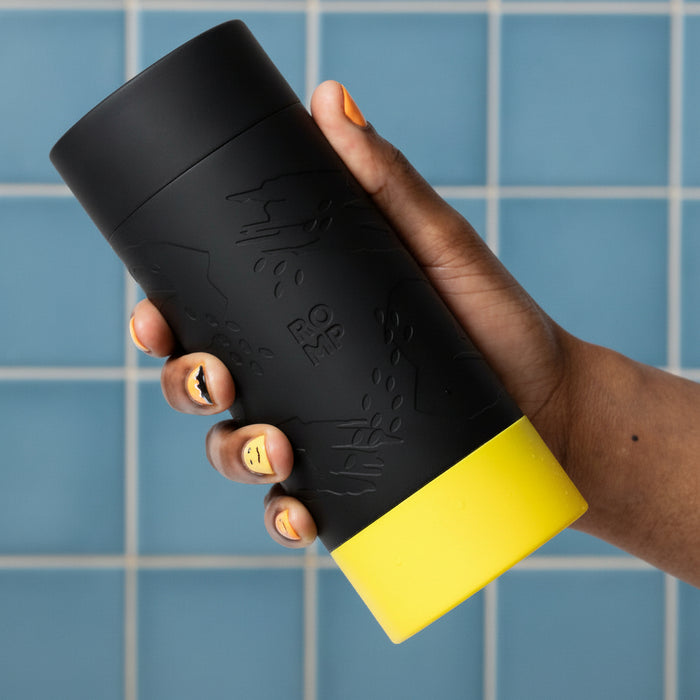 Romp Dash Manual Stroker with lid on being held by a hand on a white background