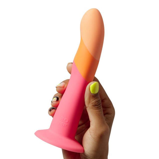 A hand with brightly colored nail polish holds up the colorful, body-safe silicone Romp Dizi Ultra Smooth 7 Inch Dildo With Suction Cup by Lovehoney. This waterproof dildo is predominantly pink with an orange and beige tip, featuring a curved, smooth surface that is perfect for p-spot and g-spot stimulation.