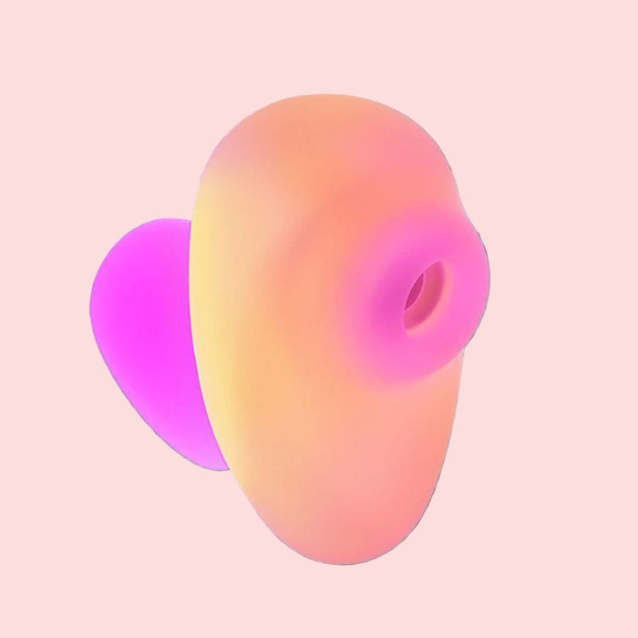 The Romp Kiss Beginner Air Pulsation Clitoral Stimulator boasts a smooth, compact 3D shape with vibrant peach, pink, and purple gradients against a dark teal background. Inspired by ergonomic design, it features a central circular indentation.