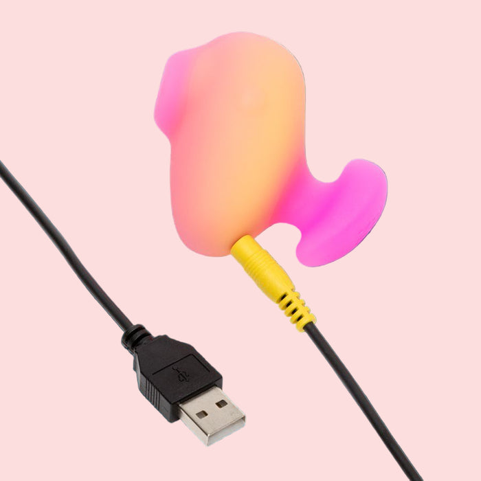 The Romp Kiss Beginner Air Pulsation Clitoral Stimulator features an ergonomic design in pink and orange with a USB cable, set against a dark teal background.