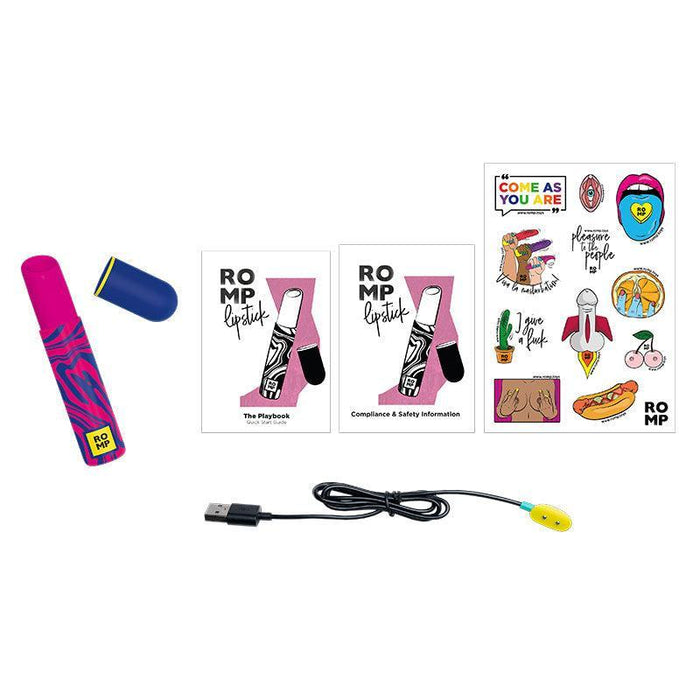 The ROMP Lipstick First Time Pleasure Air Clitoris Stimulator Vibrator by WOW, in vibrant pink and blue, rests beside its cap. It is surrounded by a playbook, a compliance and safety information booklet, playful stickers, and a USB charging cable with a yellow end. Equipped with Pleasure Air Technology, this clitoral stimulator promises delightful sensations.