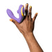 A hand with orange and black painted nails holds the Romp Reverb Pleasure Air Vibrator for G-Spot & Clitoris, featuring purple and yellow colors, against a white background.