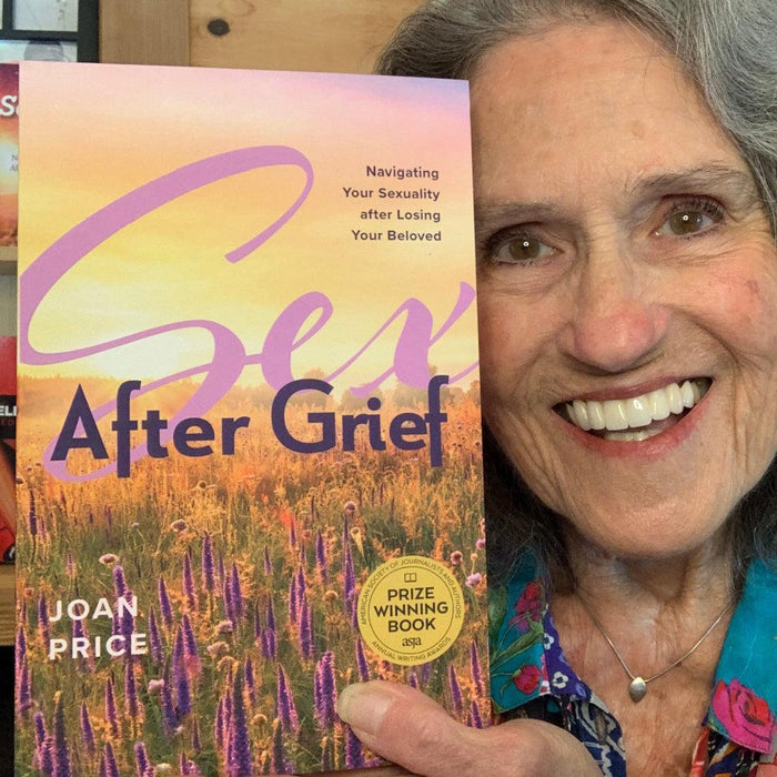 A smiling older woman holds up "Sex After Grief by Joan Price," a book about sexual reawakening after loss. The cover, featuring wildflowers and a sunset sky, invites readers to embrace intimacy again in their later years.
