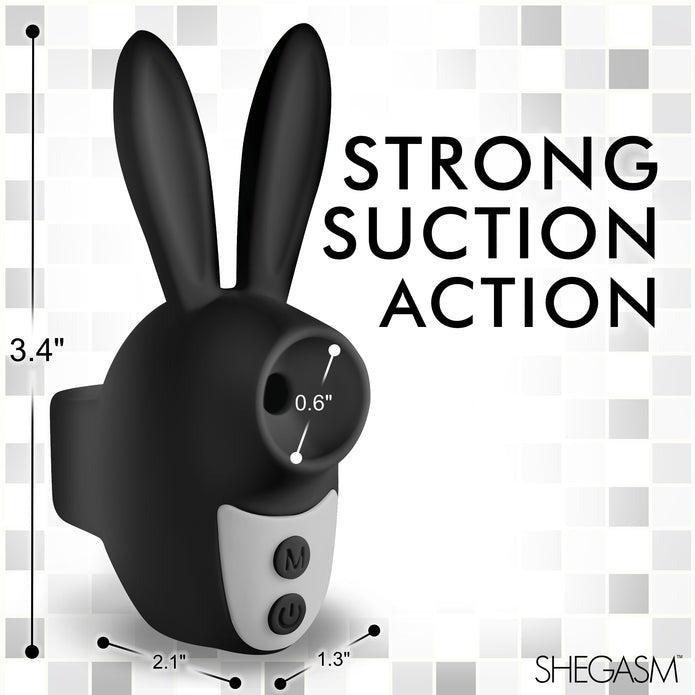 An image of a black, bunny-shaped object branded "SHEGASM" by XR Brands features ears and a 0.6-inch mouth-like suction area, along with respective measurements. The text reads "STRONG SUCTION ACTION." Crafted from body-safe silicone for beginners in vibrators, the dimensions are 3.4", 2.1", and 1.3". This product is the Shegasm Sucky Bunny Beginner Clit Stimulator.