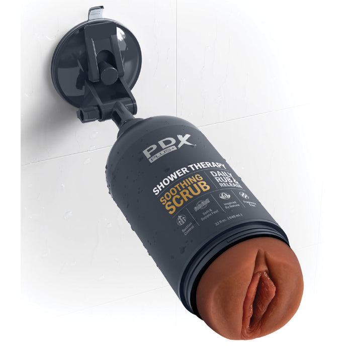 A chocolate-colored bottle labeled "Shower Therapy Discreet Realistic Stroker with Mount - Chocolate" from Pipedream Products is mounted on a shower wall with a suction cup holder. The discreet stroker design includes a soft, flesh-colored cap featuring an opening that resembles a human anatomical part.