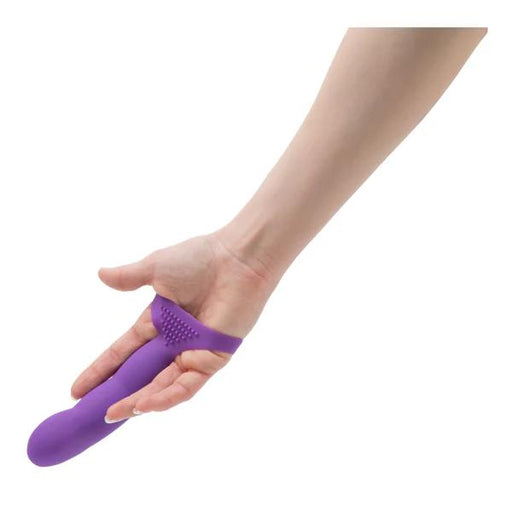 A hand with fingers extended wears the Simple and True Silicone G-Spot Finger Extender in purple, featuring a bulbous tip and textured surface for enhanced sensation. Designed for two fingers, it doubles as a G-spot stimulator against a plain white background.