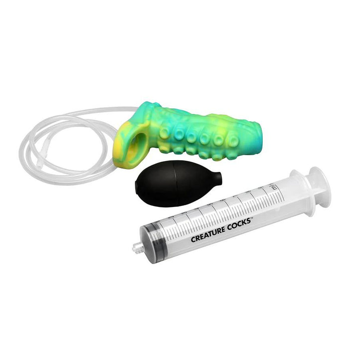 The Siphon Green Tentacle Squirting Penis Enhancer—green and yellow with a loop and tube—comes with a black bulb pump and a clear plastic “CREATURE COCKS” syringe, all displayed on a white background.
