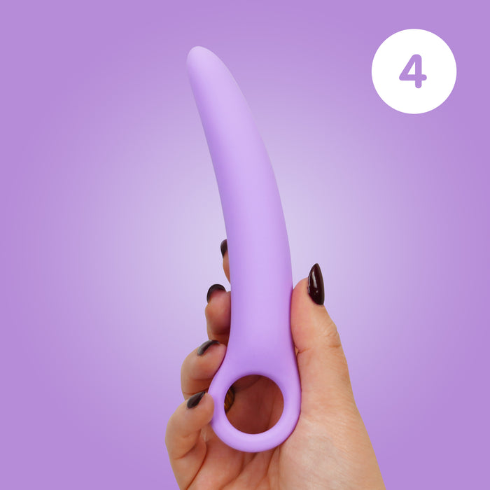 A hand with dark nail polish holds the Skins Care Curved Vaginal Dilators 3-Piece Set (Medium/Large), made of light purple medical-grade silicone with a circular handle, against a purple background. A white circle with the number 4 is in the upper right corner.
