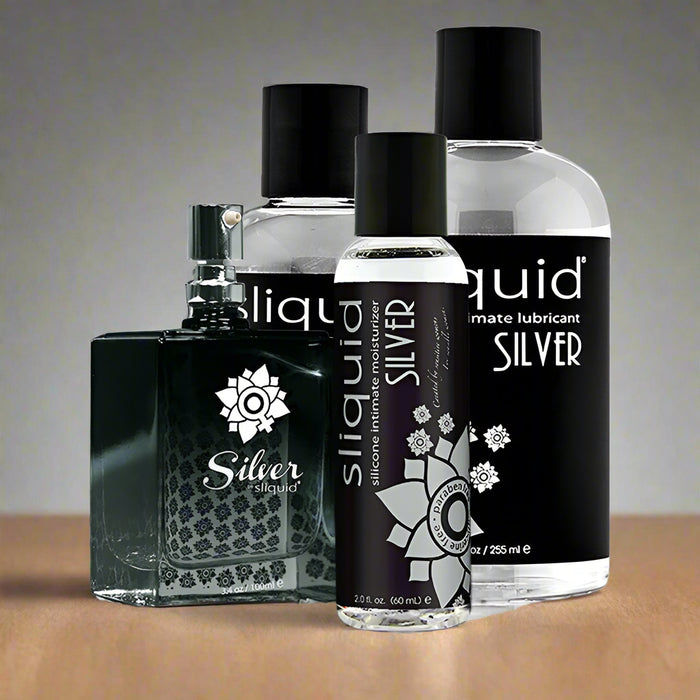 A variety of Sliquid Silver Silicone Lubricant bottles are displayed, including a larger 8.5 fl. oz. bottle, a medium-sized 4.2 fl. oz. bottle, and a smaller 2 fl. oz. travel-size bottle—all labeled under the Sliquid brand with black and gray branding, featuring long-lasting lubricant made from pharmaceutical-grade silicone for 100% waterproof use.
