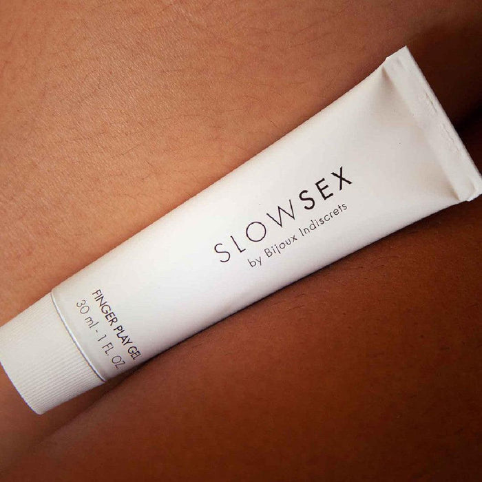 A white tube of "Bijoux Indiscrets Slow Sex Finger Play Gel for Fingering," with a hint of coconut aroma, rests on a surface. The 30 ml (1 fl oz) tube offers natural lubrication perfect for enhancing your intimate moments.