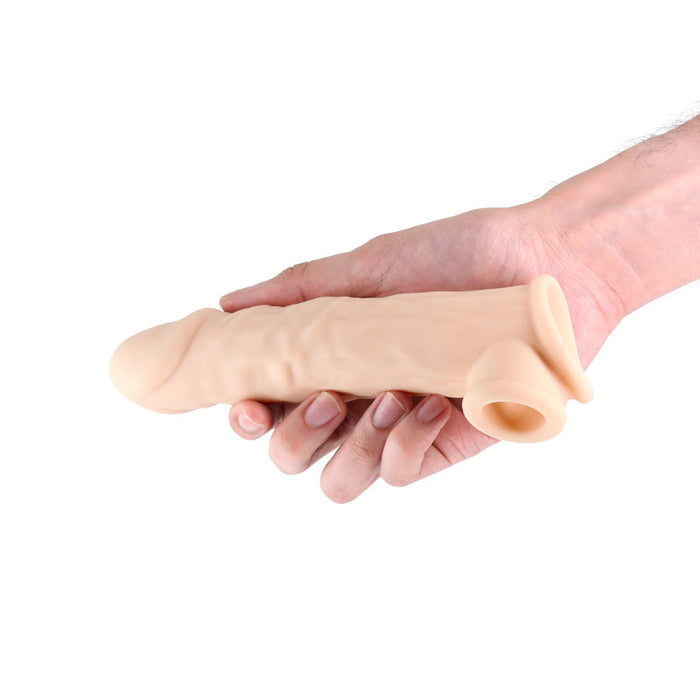 A hand holds the Renegade Annex Thin Penis Extension, a realistic flesh-toned silicone dildo with textured details and an ultra-thin sleeve, set against a white background.