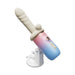 The Spinel App-Controlled, Multi-Attachment Thrusting, Vibrating & Heating Dildo Machine features a gradient blue and pink design with a beige ribbed cylindrical attachment and suction cup base for hands-free use, shown against a white background.