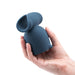 A hand holds the Stroke Silicone Penis Play Wand Attachment, a dark blue textured masturbation sleeve with an open end and smooth, rounded body—an ideal upgrade for penis pleasure—against a white background.