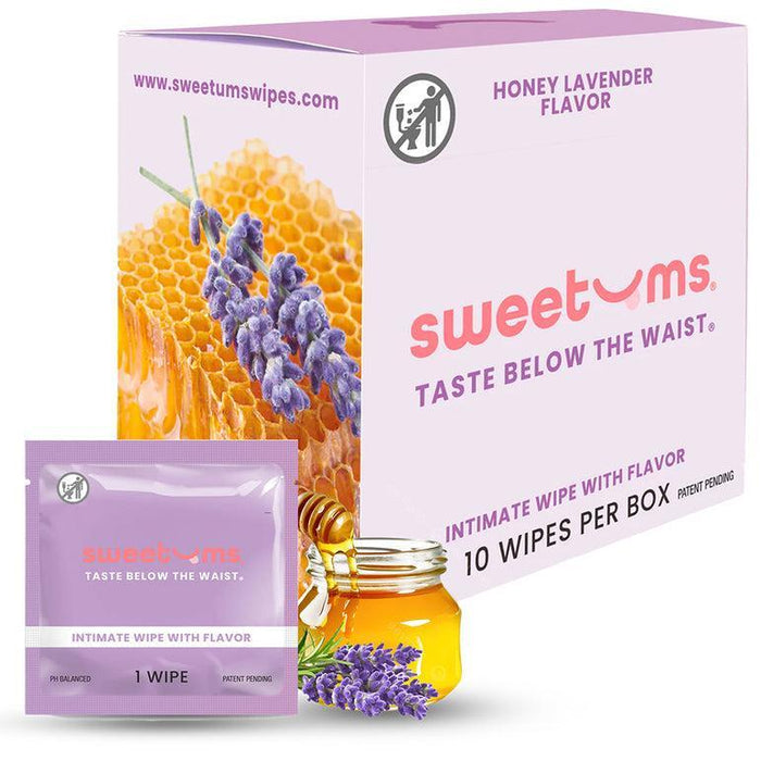 A Sweetums Flavored Intimate Wipes 10-pack is displayed in honey lavender. Made from vegan fibers, the box shows a honeycomb and lavender images, with a single wipe packet and a small jar of honey accompanied by lavender sprigs in front of the pH-balanced pack.