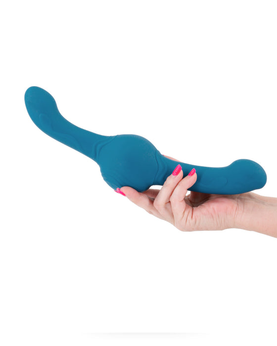 A hand with pink nail polish holding a blue, curved NS Novelties Tsunami Thrusting Shaking Gyrating Double Ended Vibrating Dildo with Remote against a white background.