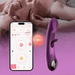 A woman smiles on a bed as a smartphone displays an app alongside the Tempo G-Spot Tapping Pressure Sensing App-Controlled Vibrator, a purple, curved device designed for g-spot stimulation. A pink gradient overlay colors the image.