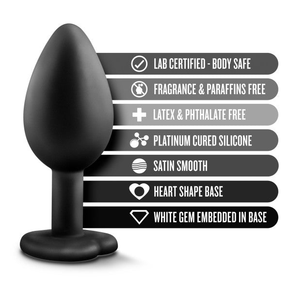 An image of the Temptasia Bling Small Silicone Butt Plug – Black by Blush, showcasing its black, heart-shaped base adorned with a dazzling white gem, along with labels highlighting its standout features: "Lab certified - body safe," "Fragrance & paraffins free," "Latex & phthalate free," and "Platinum cured satin smooth silicone.