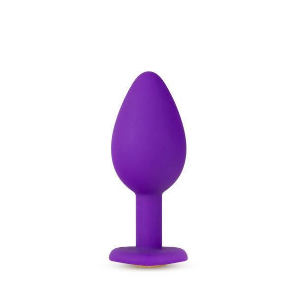 The Temptasia Bling Small Silicone Butt Plug by Blush features a smooth, tapered design and a heart-shaped base for safe insertion. Perfect for beginner users, this purple toy stands upright against a plain white background.