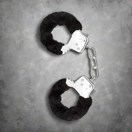A pair of sexy Blush Temptasia Furry Cuffs Handcuffs in black, isolated on a white background.