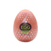 A patterned orange egg-shaped object from the Tenga Egg Disposable Penis Masturbator - Combo with green and black labeling.